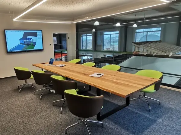 Moderner Besprechungsraum mit großem Holztisch, Designerstühlen und Präsentationsmonitor.