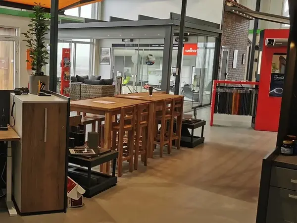 Moderner Ausstellungsraum mit Holztisch, Stühlen und Glaswänden für Fensterberatung.