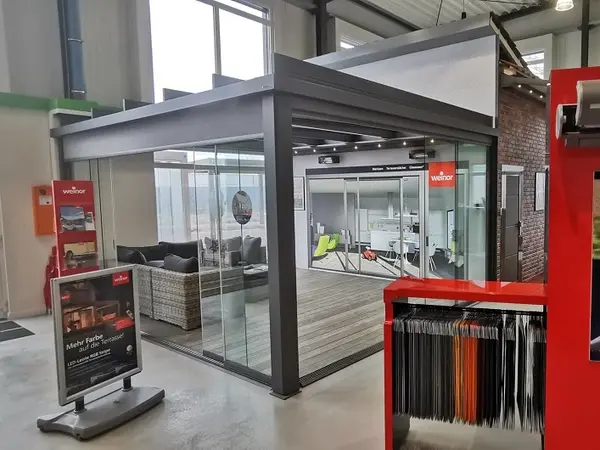 Moderne Terrassenüberdachung aus Glas und Aluminium in einem Ausstellungsraum.