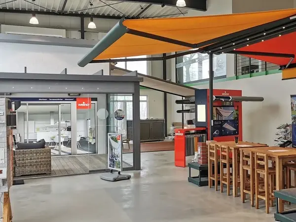 Moderne Ausstellung für Terrassenüberdachungen und Markisen mit Sitzbereich und Infostand.