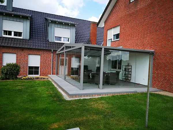 Moderner Wintergarten mit Glasüberdachung an einem Einfamilienhaus mit Garten.