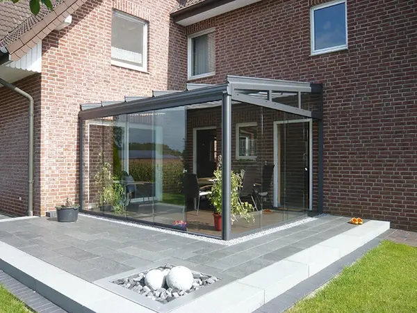Moderner Wintergarten aus Glas und Aluminium an einem Einfamilienhaus mit Terrasse.
